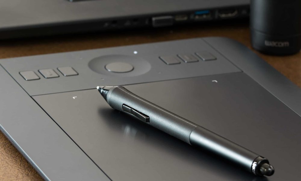Svart digital ritplatta ligger på ett bord med en svart penna för digitala ritplattor ovanpå.